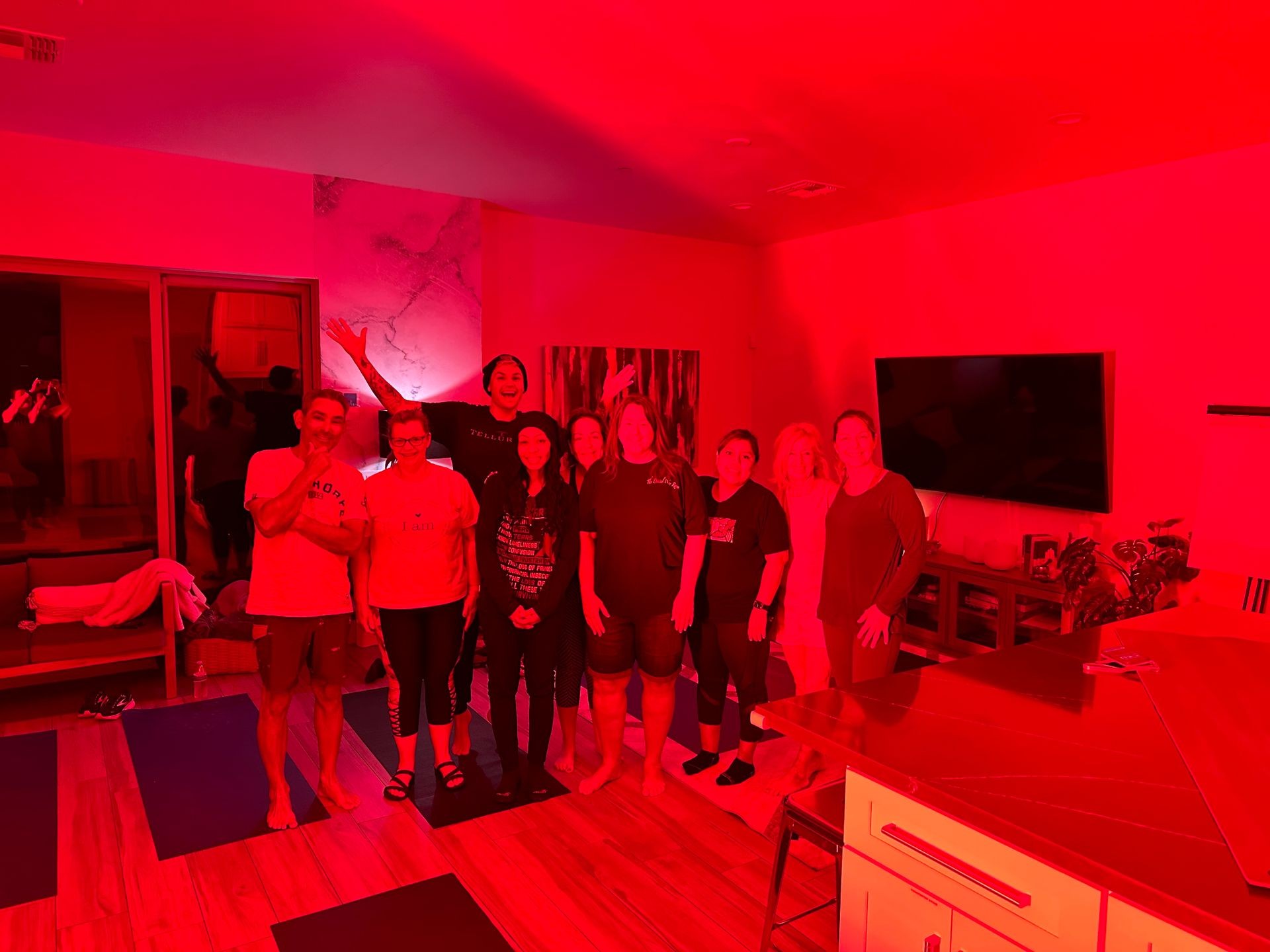 Group of people standing together indoors, illuminated by red lighting.